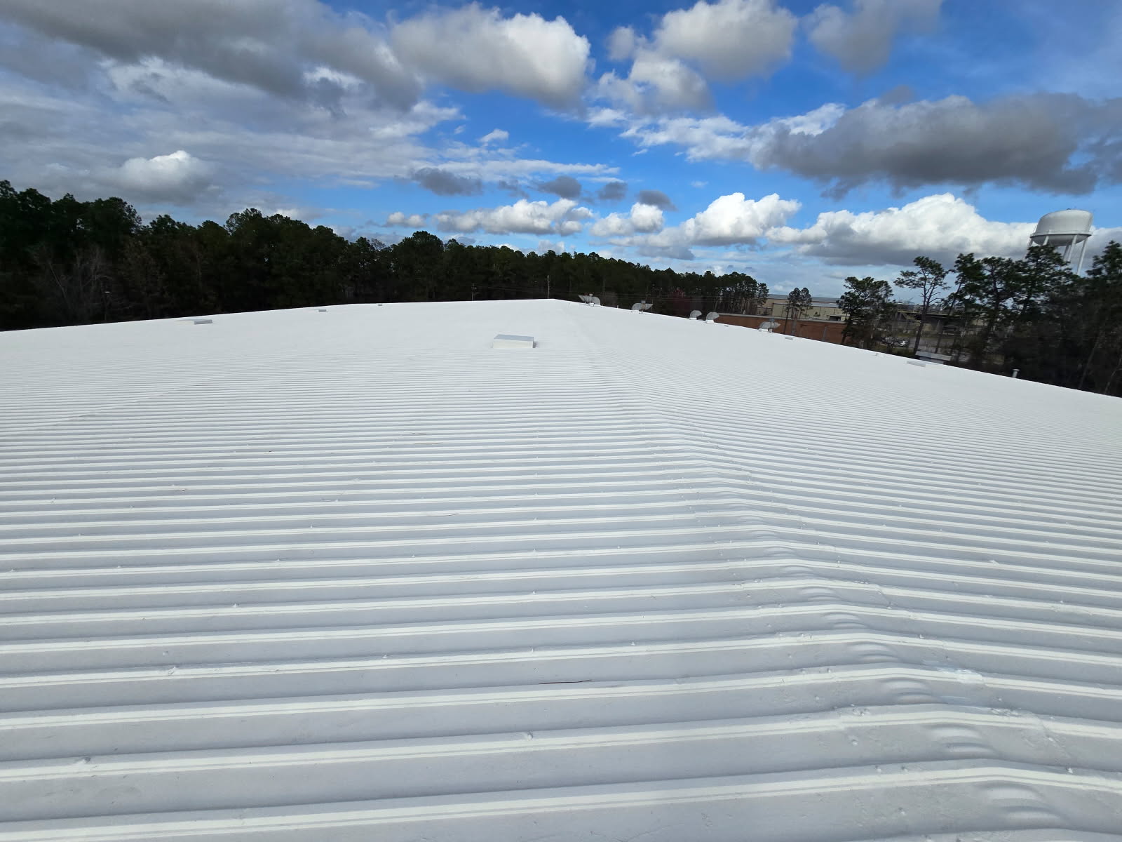 White silicone coating on standing-seam metal commercial roof