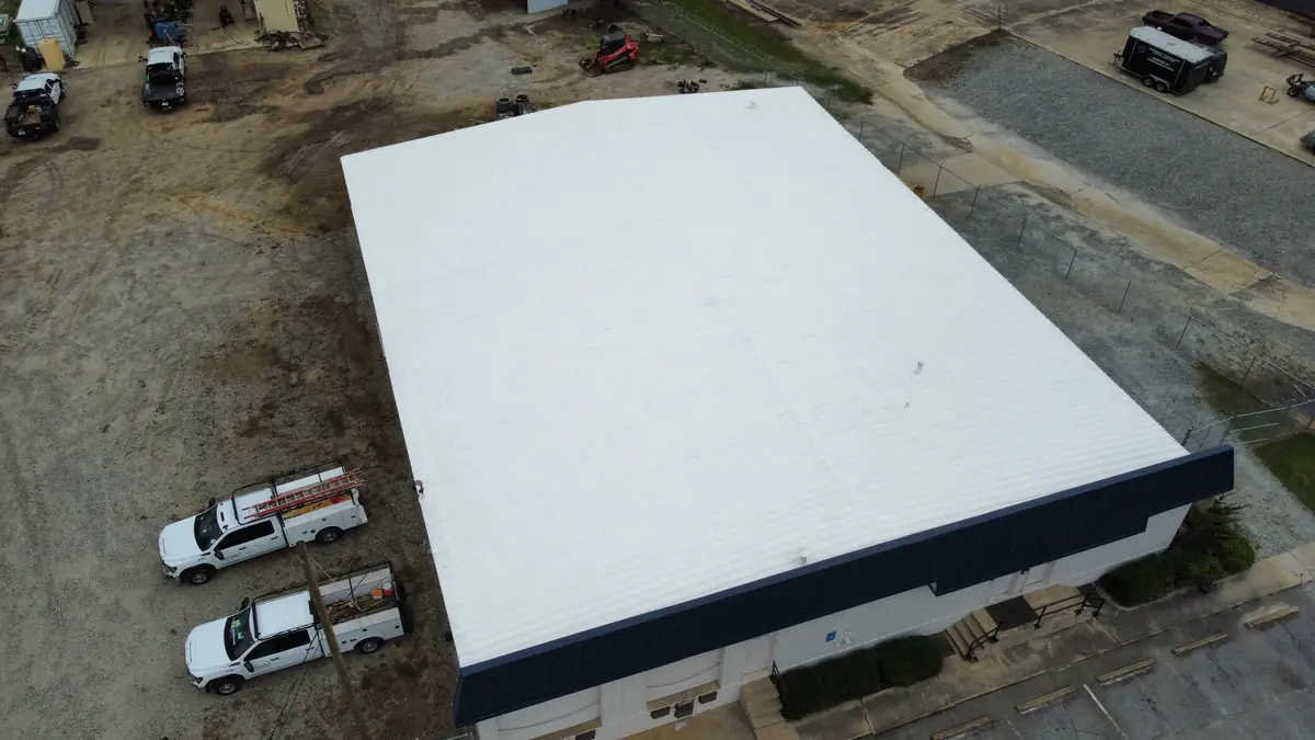 Commercial warehouse roof coating — aerial view with company trucks